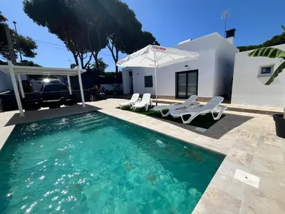 a swimming pool with chairs and an umbrella at Villa Verano in Novo Sancti Petri