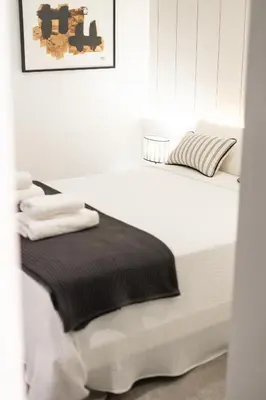 a white room with a bed with a black blanket at AvantiStays Porta Coeli con PARKING GRATIS in Sanlúcar de Barrameda