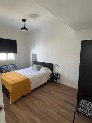 a bedroom with a bed with a yellow blanket on it at Apartamento cerca del paseo marítimo in Rota