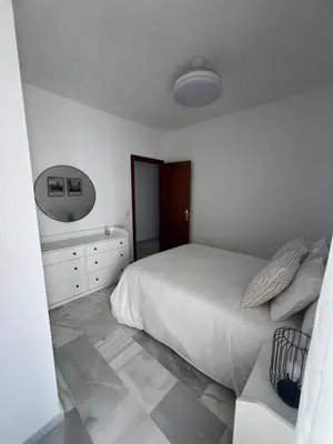 a white bedroom with a bed and a mirror at Apartamento Relax Centro in Sanlúcar de Barrameda