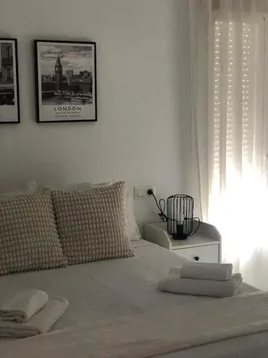 a white bedroom with a bed with towels on it at Apartamento Relax Centro in Sanlúcar de Barrameda