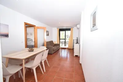 a dining room and living room with a table and chairs at Dúo de bajos con jardín, juntos y climatizados en Aldea del Coto in Novo Sancti Petri