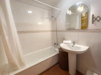 a bathroom with a sink and a bath tub and a mirror at Dúo de bajos con jardín, juntos y climatizados en Aldea del Coto in Novo Sancti Petri