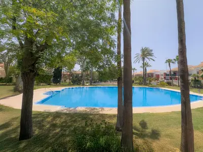 a swimming pool in a yard with trees at Dúo de bajos con jardín, juntos y climatizados en Aldea del Coto in Novo Sancti Petri