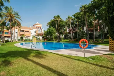 a swimming pool with a red sign in the grass at Dúo de bajos con jardín, juntos y climatizados en Aldea del Coto in Novo Sancti Petri