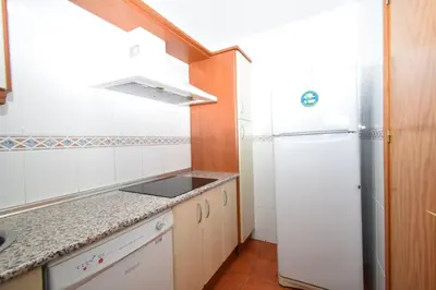 a small kitchen with a refrigerator and a sink at Dúo de bajos con jardín, juntos y climatizados en Aldea del Coto in Novo Sancti Petri