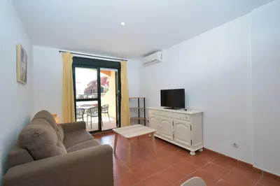a living room with a couch and a tv at Dúo de bajos con jardín, juntos y climatizados en Aldea del Coto in Novo Sancti Petri