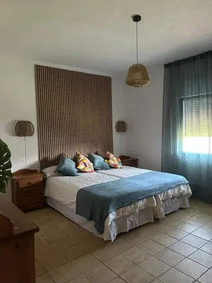 a bedroom with a large bed with blue pillows at Villa Palmeras in Conil de la Frontera