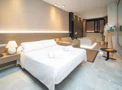 a bedroom with a large white bed and a bathroom at Hotel Barrameda in Sanlúcar de Barrameda