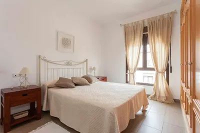 a white bedroom with a bed and a window at casa jaramar in Sanlúcar de Barrameda