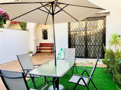 a table and chairs with an umbrella in a yard at casa jaramar in Sanlúcar de Barrameda