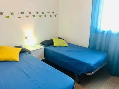 two beds in a room with blue sheets and yellow pillows at casa jaramar in Sanlúcar de Barrameda
