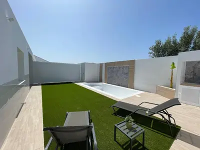 a backyard with a lawn and a swimming pool at Jaimar12 in Novo Sancti Petri