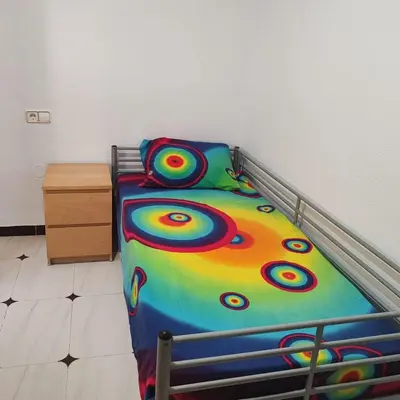 a bed with a colorful comforter in a bedroom at Casa Álamo in Puerto Real