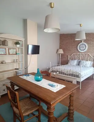 a living room with a table and a bed at Ático Vicario 11 in El Puerto de Santa María