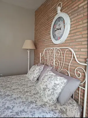 a bedroom with a bed with a clock on a brick wall at Ático Vicario 11 in El Puerto de Santa María