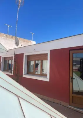 a red building with a door and windows at Ático Vicario 11 in El Puerto de Santa María