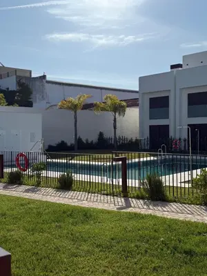 a fence in front of a building with a swimming pool at ESPECTACULAR PISO EN PALACIO Preferiblemente familias y mayores de treinta años in El Puerto de Santa María