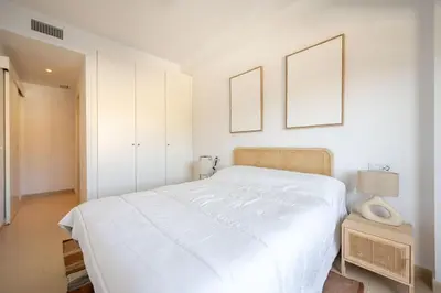 a white bedroom with a bed and two pictures on the wall at Centro con piscina y cerca de la estación de tren in El Puerto de Santa María