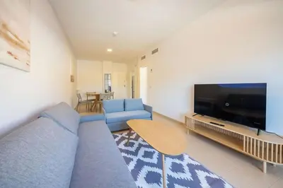 a living room with a blue couch and a flat screen tv at Centro con piscina y cerca de la estación de tren in El Puerto de Santa María