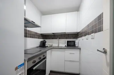 a white kitchen with a sink and a microwave at Centro con piscina y cerca de la estación de tren in El Puerto de Santa María