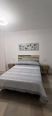 a bed in a white room with two tables at Apartamento Prieta in Jerez de la Frontera
