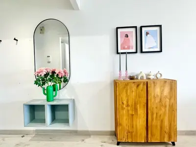 a mirror and a vase with flowers on a table at Atreb San Fernando in San Fernando