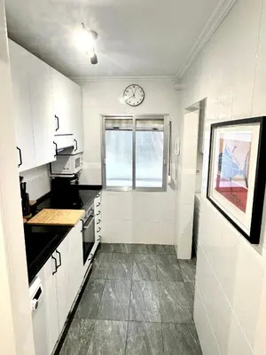a kitchen with white cabinets and a clock on the wall at Atreb San Fernando in San Fernando