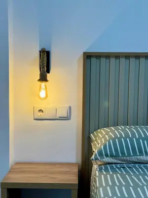 a light on a wall next to a bed at Apartamento Guadalquivir 34 in Sanlúcar de Barrameda