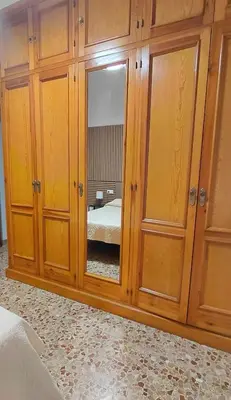 a large wooden cabinet with a mirror in a bedroom at Villa Caheta in Chipiona