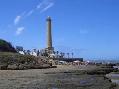 a lighthouse on the beach with people on the beach at Villa Caheta in Chipiona