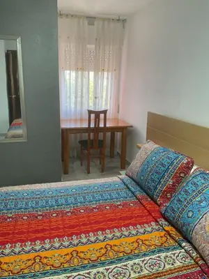 a bedroom with a bed and a table with a chair at Casa Marejada in Puerto Real