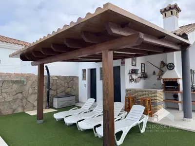 a patio with white chairs and a wooden pergola at Villa Cañuela in Chiclana de la Frontera