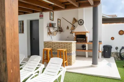 a patio with white chairs and a fireplace at Villa Cañuela in Chiclana de la Frontera