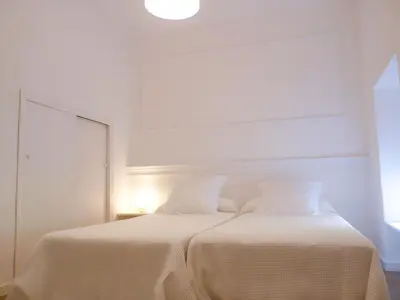 a white bedroom with a bed with two pillows at Casa Palacio Morla y Melgarejo in Jerez de la Frontera