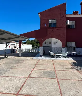 a red building with two benches in front of it at villa los gallos 10 in Chiclana de la Frontera