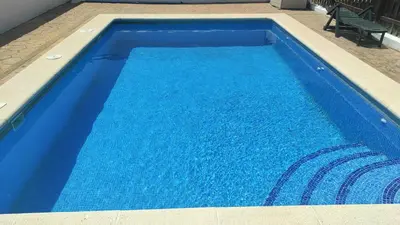a large blue swimming pool with a bench in it at CASA ALBA in Conil de la Frontera