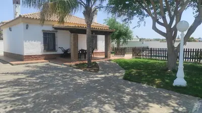 a small white house with a fence and trees at CASA ALBA in Conil de la Frontera