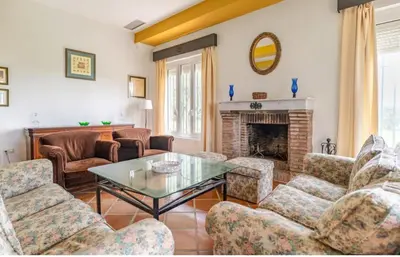 a living room with chairs and a table and a fireplace at Family country house with pool in Conil in Cádiz