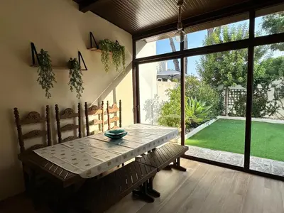 a dining room with a table and a view of a yard at Casa de playa nueva y luminosa in Chiclana de la Frontera