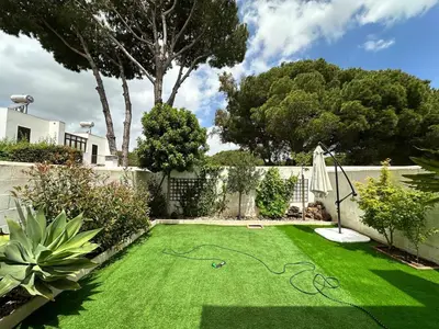 a garden with green grass and trees and a fence at Casa de playa nueva y luminosa in Chiclana de la Frontera