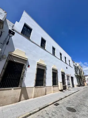 a white building with barred windows on a street at GATU Rubí in El Puerto de Santa María