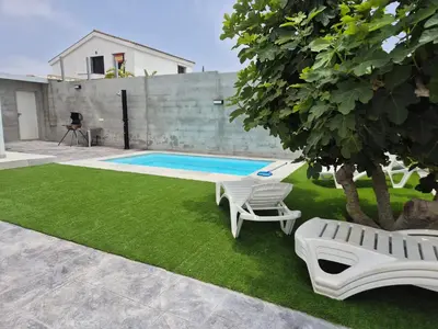 a yard with a pool and two chairs and a tree at Casitalola in Conil de la Frontera
