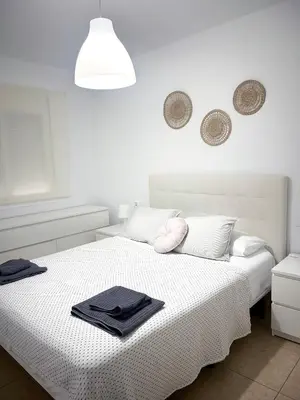 a white bedroom with two beds with towels on it at Apto cerca de playa Regla con garaje in Chipiona
