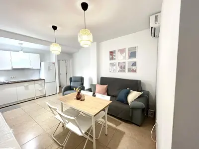 a living room with a table and a couch at Apto cerca de playa Regla con garaje in Chipiona