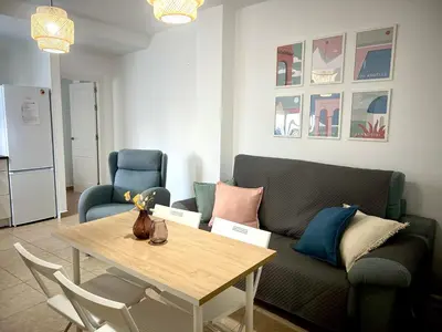 a living room with a couch and a table and chairs at Apto cerca de playa Regla con garaje in Chipiona