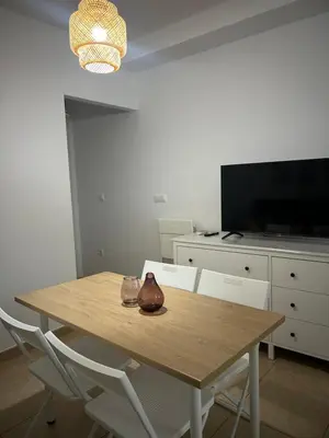 a dining room table with two chairs and a television at Apto cerca de playa Regla con garaje in Chipiona