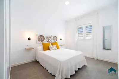 a white bedroom with a large bed with yellow pillows at Sauz A in Novo Sancti Petri