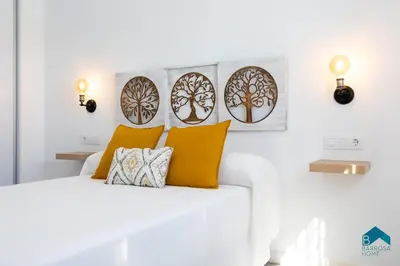 a white bedroom with a white bed with orange pillows at Sauz A in Novo Sancti Petri