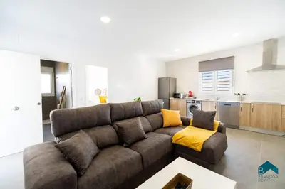 a living room with a brown couch and a kitchen at Sauz A in Novo Sancti Petri
